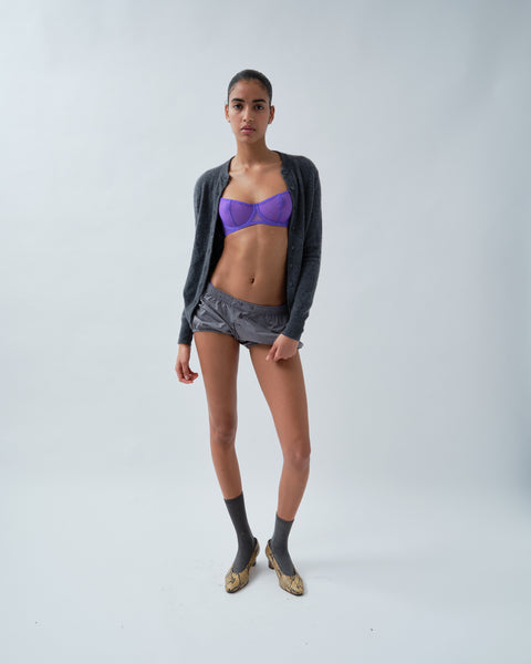 Woman wearing purple bra, grey shorts and grey cardigan