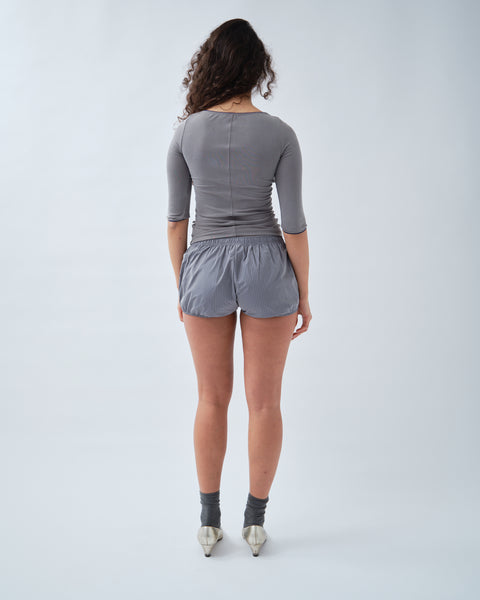 Back of woman wearing grey top with grey shorts

