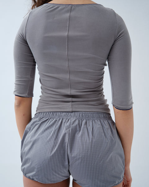 Back of woman wearing grey ribbed top with grey check shorts