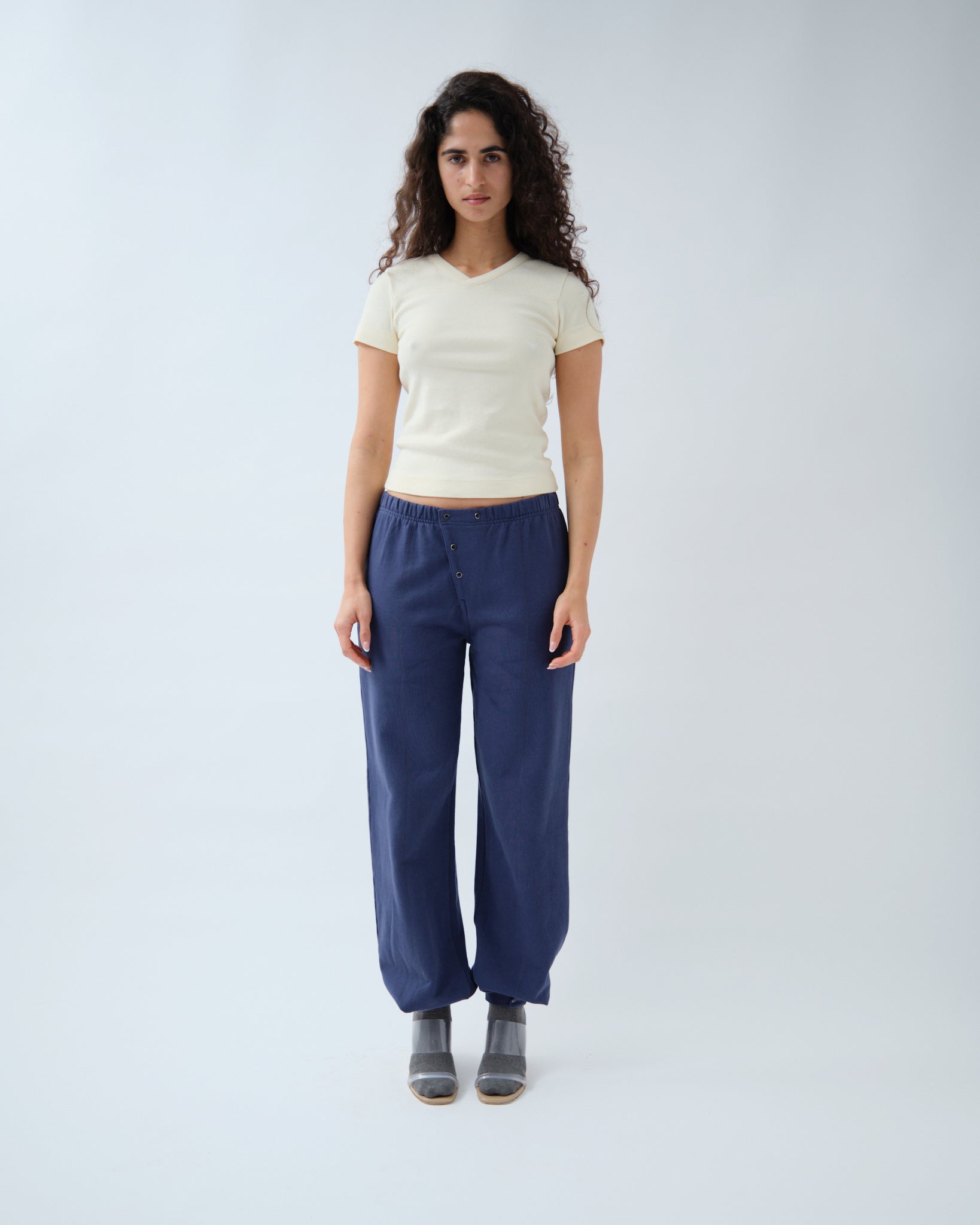 Front of woman wearing yellow v-neck tshirt with navy trousets