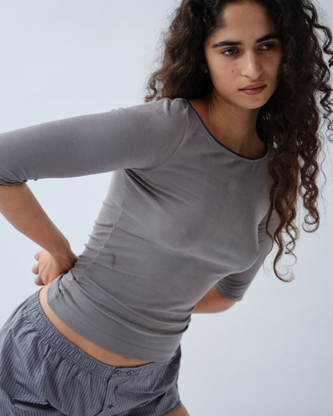 Woman wearing grey ribbed 3/4 sleeve top with navy blue detailing