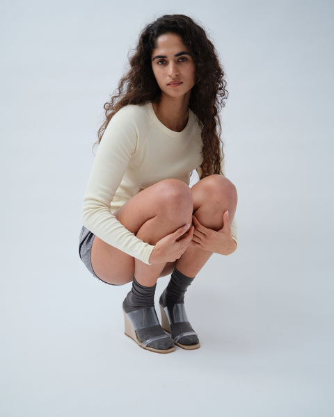 Woman crouching wearing yellow long sleeve top
