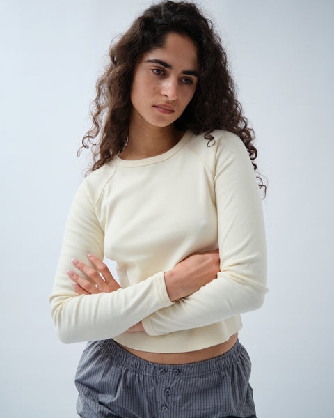 Front of woman wearing yellow long sleeve tshirt with grey shorts and arms crossed
