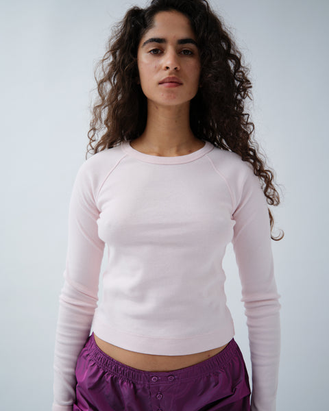 Front of woman wearing light pink long sleeve tshirt with purple shorts