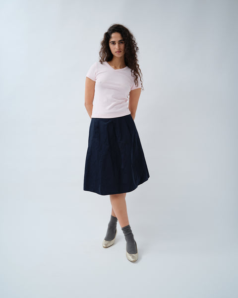 Woman wearing pink v-neck tshirt with navy skirt
